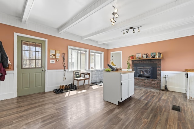 1568 Hill Rd, Canaan, ME 04924 - foyer entrance featuring a wood stove, wainscoting, beamed ceiling, and dark wood-style flooring
