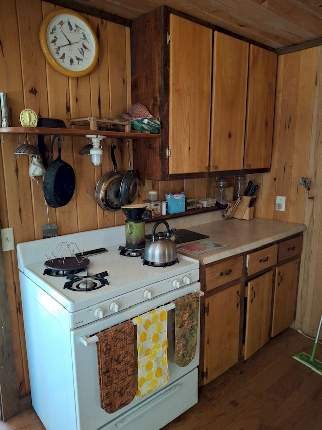 27 Kingman Beach Rd, Osborn, ME 04605 - kitchen featuring white range with gas stovetop, wood walls, wood finished floors, light countertops, and brown cabinets