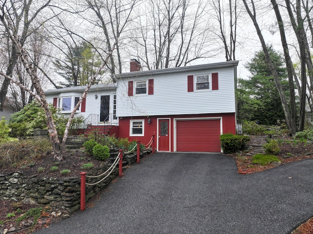 11 Moreau Ave, Lewiston, ME 04240 - split level home with a chimney, asphalt driveway, and a garage