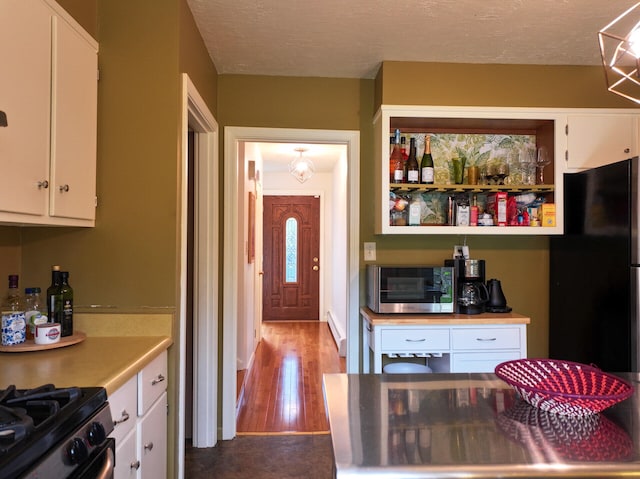 11 Moreau Ave, Lewiston, ME 04240 - kitchen featuring white cabinets, light countertops, freestanding refrigerator, and a baseboard heating unit