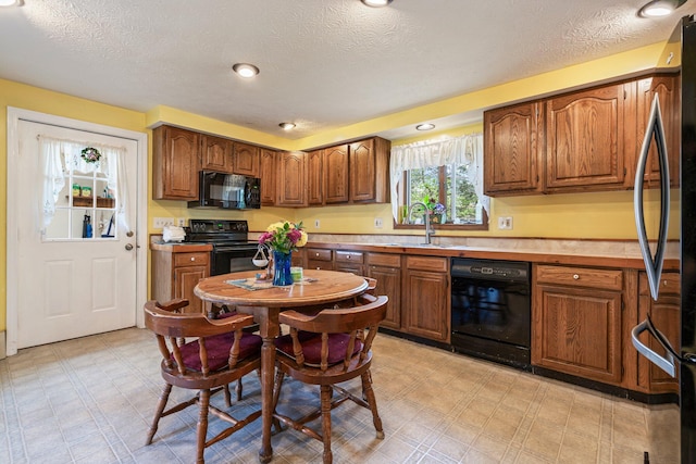 kitchen with black appliances, a sink, light floors, a textured ceiling, and light countertops