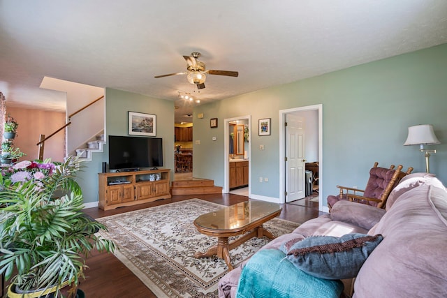 living room with a ceiling fan, wood finished floors, stairway, and baseboards
