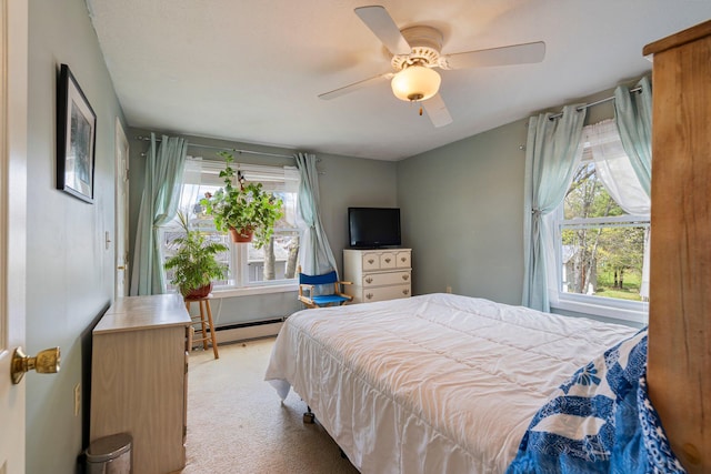 bedroom with a baseboard radiator, multiple windows, light carpet, and ceiling fan