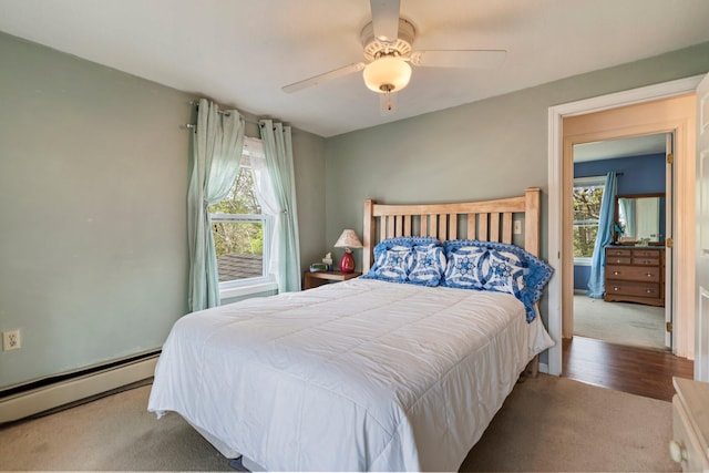 carpeted bedroom with baseboard heating, multiple windows, and ceiling fan
