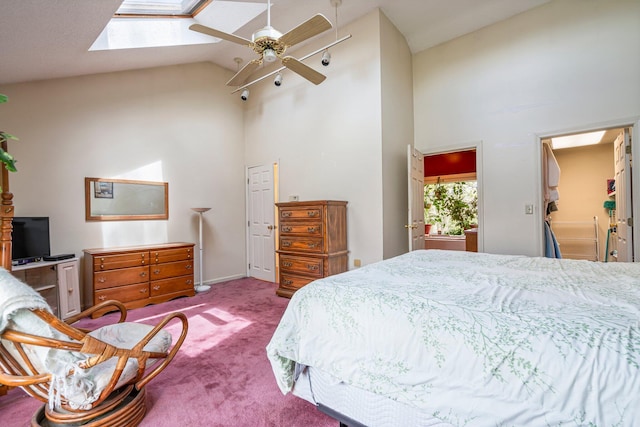 carpeted bedroom with high vaulted ceiling, a skylight, and a ceiling fan