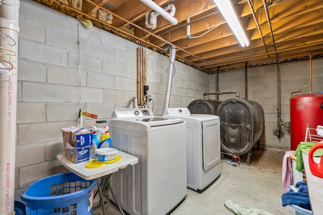 washroom featuring separate washer and dryer, oil tank, water heater, and concrete block wall