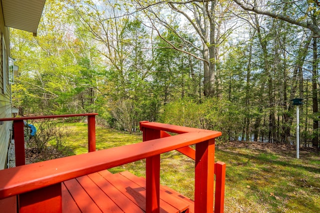wooden deck with a view of trees and a lawn