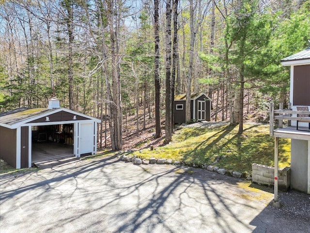 1270 Main St, Mount Desert, ME 04660 - view of patio with a shed, an outdoor structure, a detached garage, and a view of trees