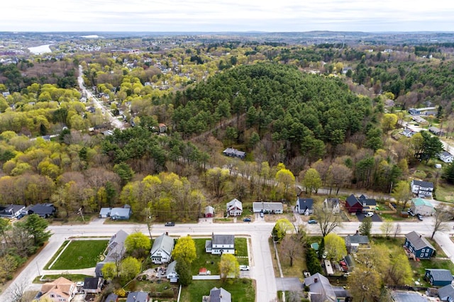 view of property location with nearby suburban area and a heavily wooded area