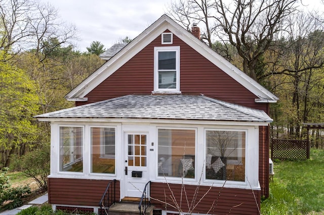 view of front of home with a shingled roof, a chimney, and entry steps