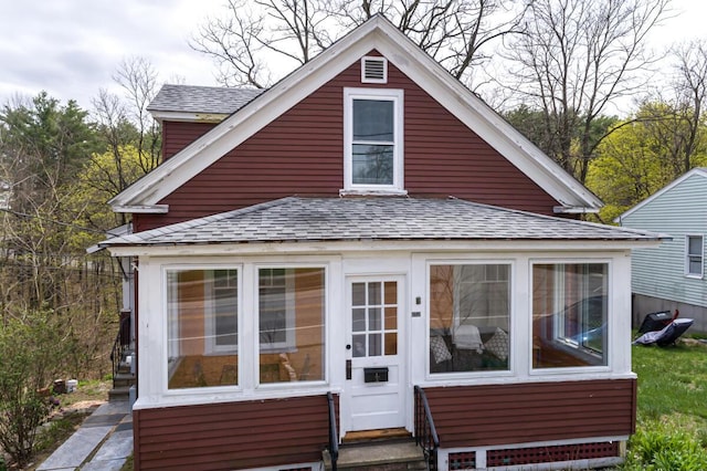 view of front facade with roof with shingles and a sunroom