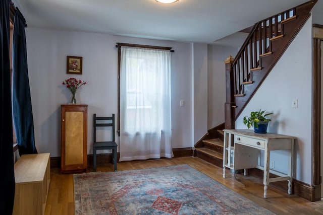 entrance foyer featuring wood finished floors, stairway, and baseboards