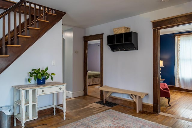 foyer featuring baseboards, hardwood / wood-style floors, and stairs
