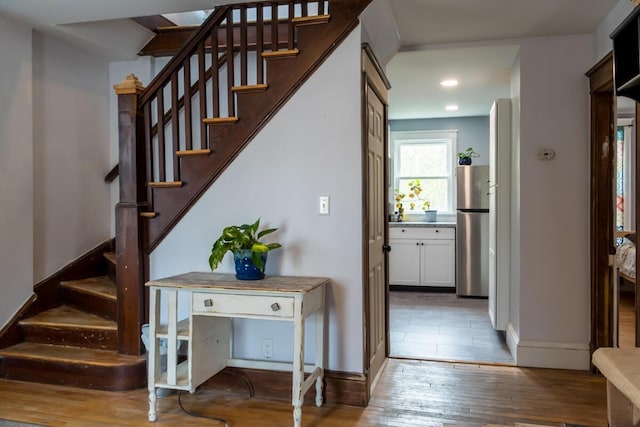 staircase featuring hardwood / wood-style floors, baseboards, and recessed lighting