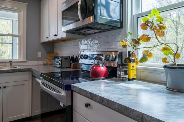 kitchen featuring appliances with stainless steel finishes, healthy amount of natural light, decorative backsplash, and white cabinetry