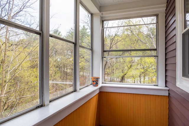 unfurnished sunroom featuring plenty of natural light, wainscoting, and wooden walls