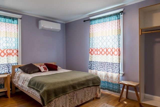 bedroom featuring an AC wall unit, wood finished floors, and crown molding