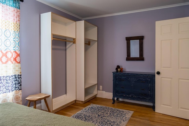 bedroom featuring wood finished floors, ornamental molding, and baseboards