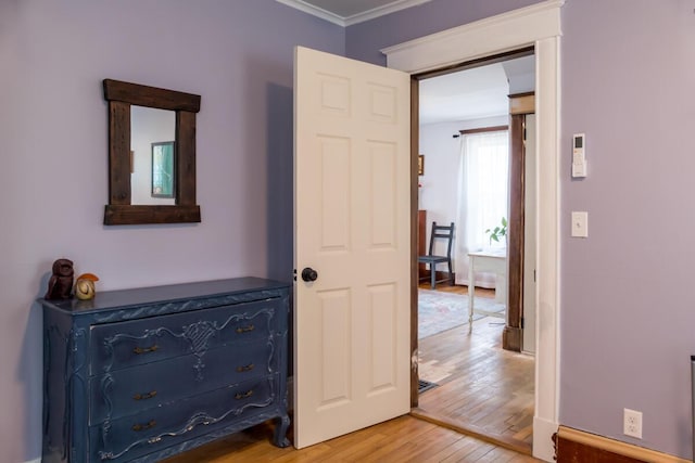 hallway with light wood-type flooring and ornamental molding