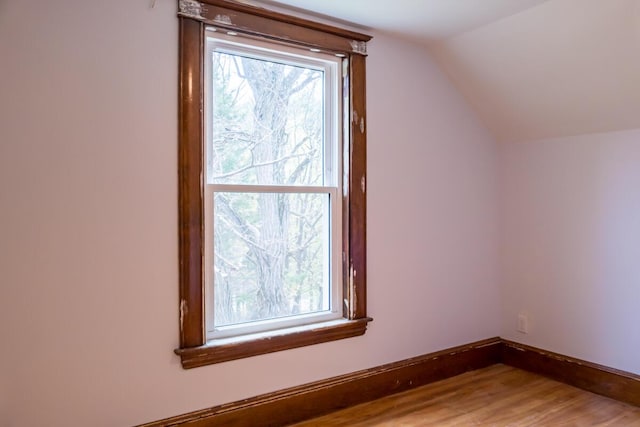 additional living space with lofted ceiling, baseboards, and light wood-style floors