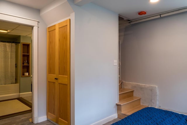 staircase with wood finished floors, baseboards, and recessed lighting