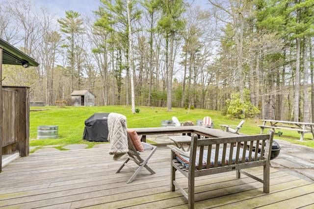 deck featuring a yard, an outbuilding, a storage shed, and a grill
