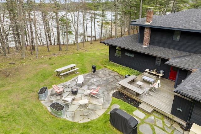 view of green lawn with an outdoor fire pit, a deck, and a patio