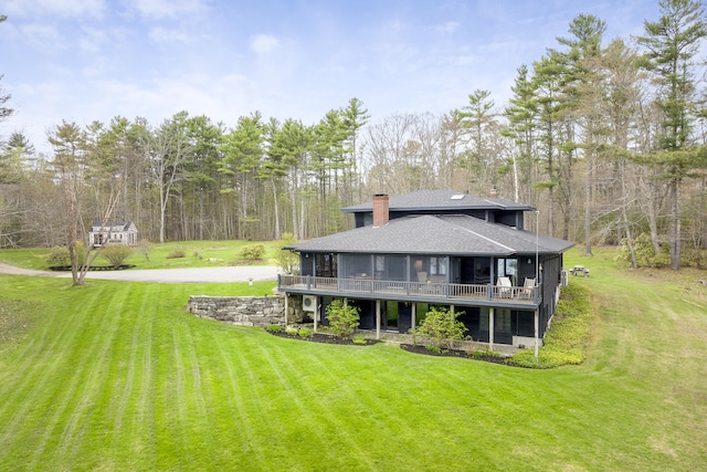 back of property with a shingled roof, a yard, a chimney, and a deck