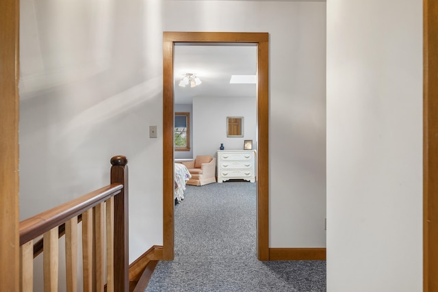 hall with carpet flooring, baseboards, and an upstairs landing