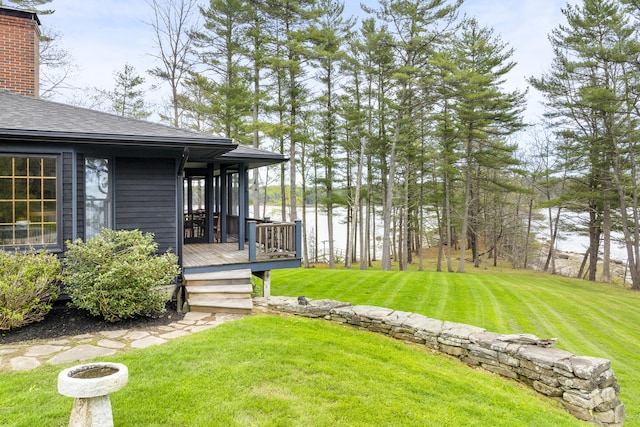 view of green lawn featuring a deck with water view