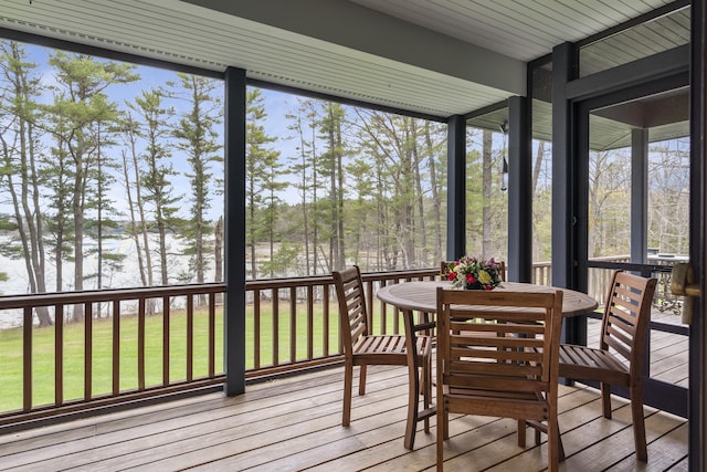 sunroom with a water view, outdoor dining space, and healthy amount of natural light