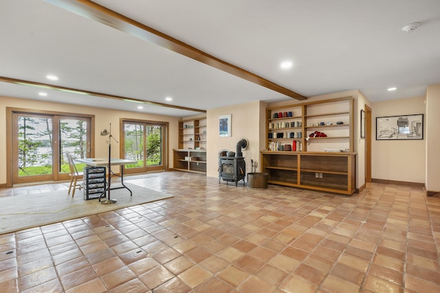 foyer entrance with a wood stove, recessed lighting, beam ceiling, and baseboards