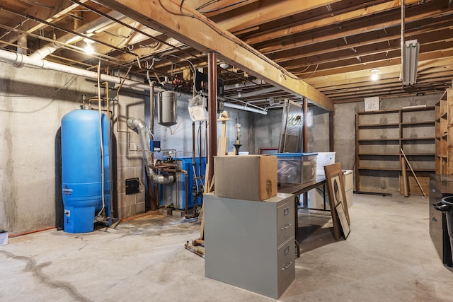 unfinished below grade area featuring a water pressure tank and a heating unit