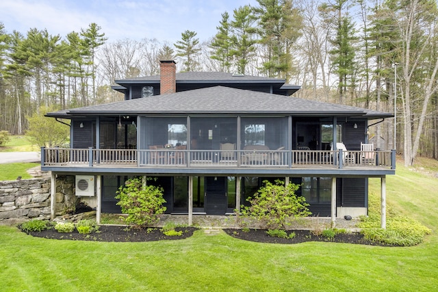 back of house with roof with shingles, a chimney, a lawn, a sunroom, and a deck