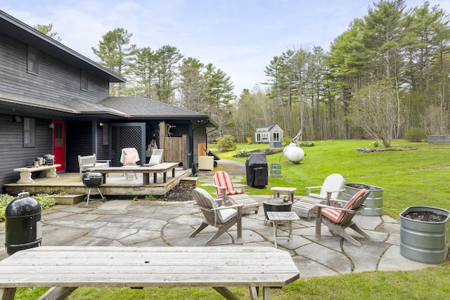 wooden deck with a yard, a patio area, and an outbuilding