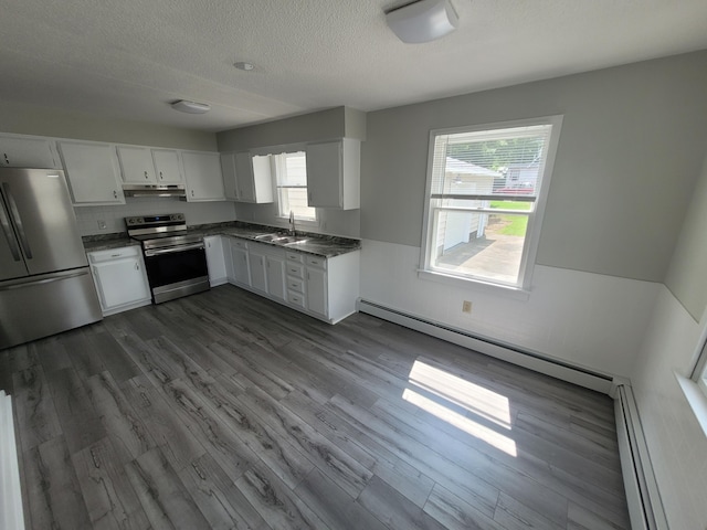110 Lincoln St, Old Town, ME 04468 - kitchen featuring appliances with stainless steel finishes, a sink, dark countertops, under cabinet range hood, and a baseboard radiator