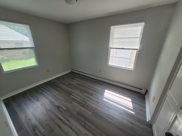110 Lincoln St, Old Town, ME 04468 - empty room with baseboard heating, dark wood-style floors, plenty of natural light, and baseboards