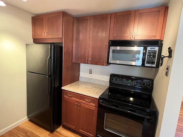 kitchen with black appliances, light wood-style floors, baseboards, and light stone counters