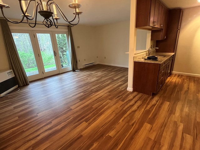 kitchen with a chandelier, a sink, a baseboard radiator, dark wood finished floors, and baseboards