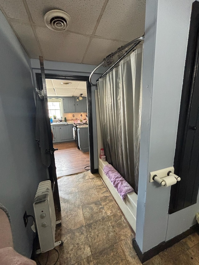 623 Gore Rd, Otisfield, ME 04270 - full bathroom featuring a drop ceiling, radiator heating unit, stone finish flooring, and shower / bathtub combination with curtain