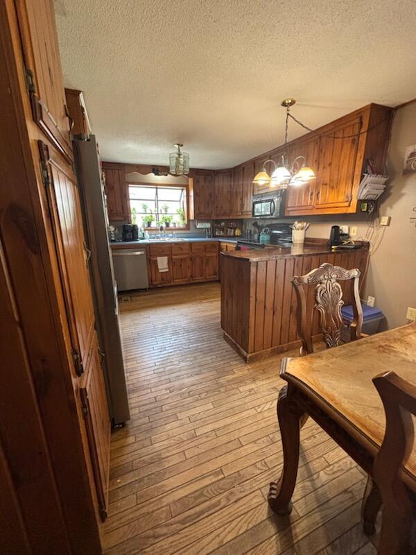 623 Gore Rd, Otisfield, ME 04270 - kitchen with a peninsula, light wood-style floors, brown cabinets, a textured ceiling, and stainless steel dishwasher