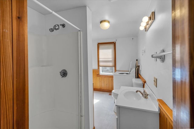 bathroom featuring a stall shower, wainscoting, vanity, wooden walls, and toilet