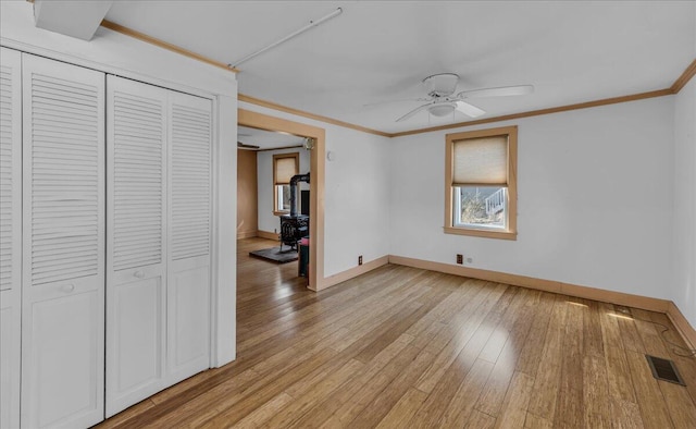 unfurnished bedroom with light wood-style flooring, baseboards, a closet, and crown molding