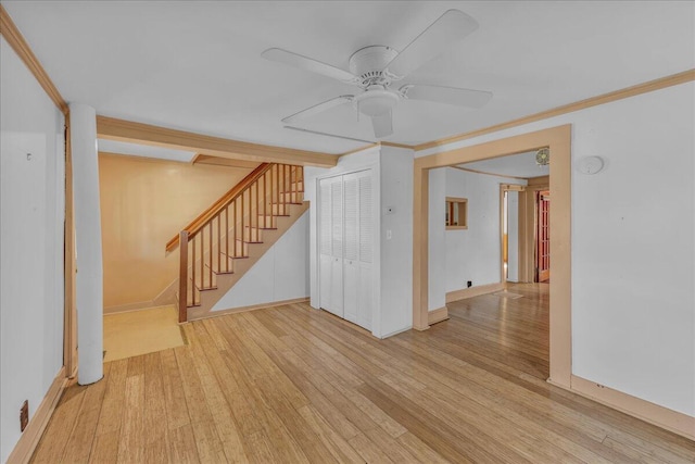empty room featuring wood finished floors, ceiling fan, stairs, and crown molding