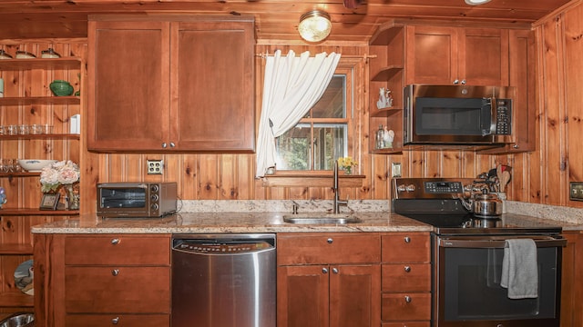 124 Alpine Village Rd, Harrison, ME 04040 - kitchen featuring stainless steel appliances, a sink, brown cabinets, light stone counters, and wood walls