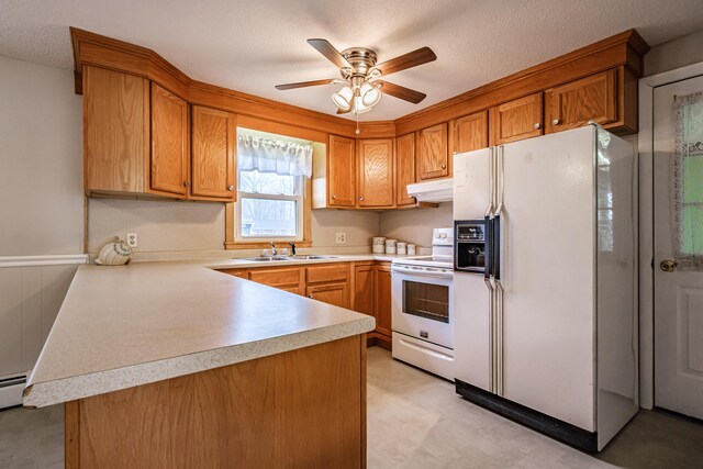 kitchen featuring white appliances, under cabinet range hood, a sink, light countertops, and brown cabinets