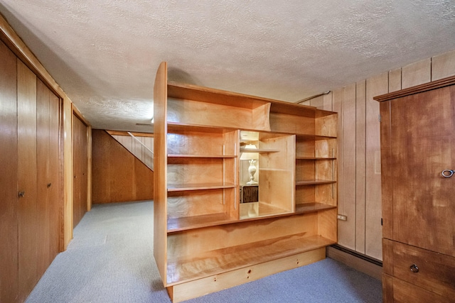 additional living space with carpet, wood walls, and a textured ceiling