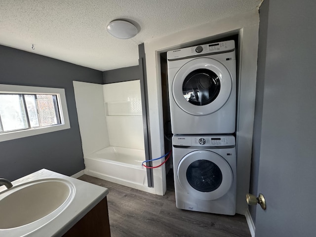 113 Sandy Beach Rd, Glenburn, ME 04401 - laundry area with stacked washing machine and dryer, dark wood-style floors, a textured ceiling, and baseboards