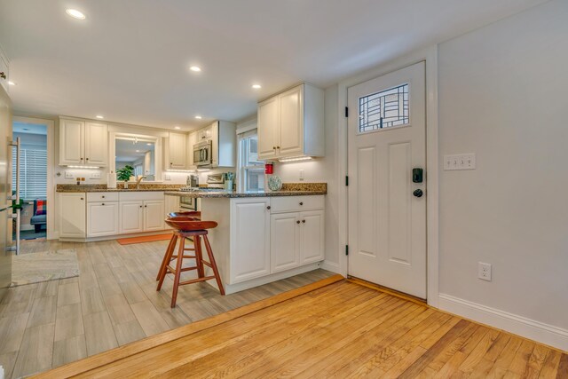 4 Union Ave, Old Orchard Beach, ME 04064 - kitchen featuring stainless steel appliances, white cabinets, light wood finished floors, a kitchen breakfast bar, and recessed lighting