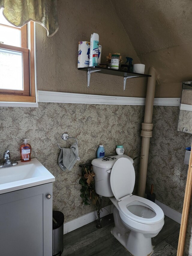 bathroom with lofted ceiling, vanity, wood finished floors, toilet, and baseboards